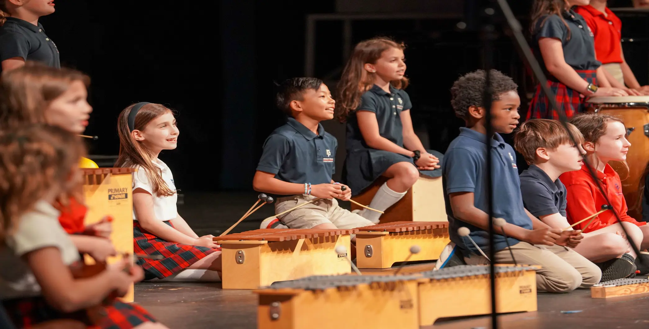Children play xylophones on a stage